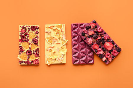 Handmade chocolate bars with fruits, berries and nuts on color backgroundの写真素材