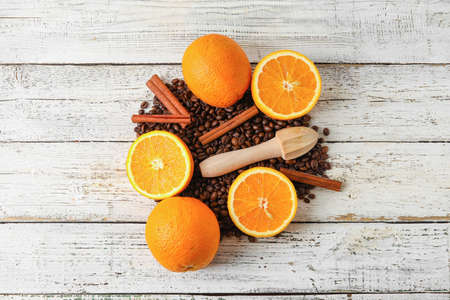 Composition with coffee beans and fresh oranges on light wooden background