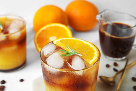 Glasses of tasty coffee with orange juice on light background, closeup