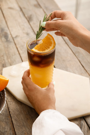 Woman decorating glass of tasty coffee with rosemary, closeup