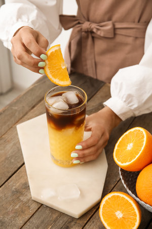 Woman decorating glass of tasty coffee with orange, closeupの写真素材