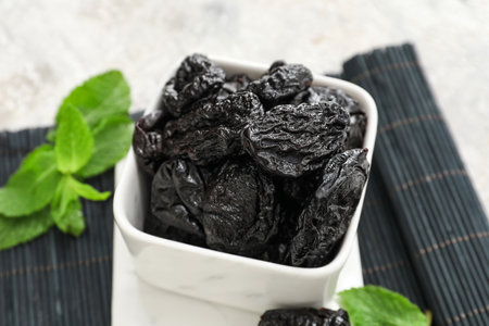 Bowl with tasty prunes on light background, closeupの写真素材