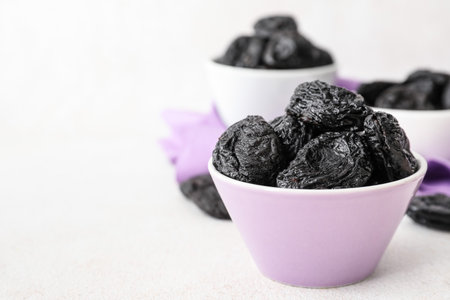 Bowl with tasty prunes on light background, closeupの写真素材