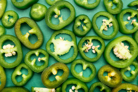 Slices green jalapeno peppers on color backgroundの写真素材
