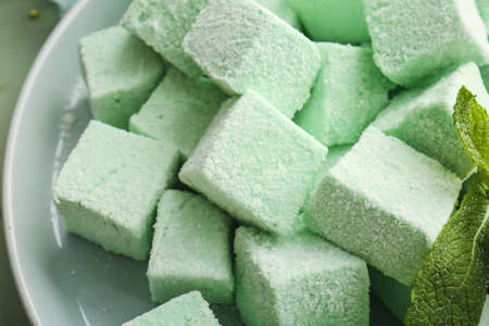 Plate with tasty sweet marshmallows and mint on color wooden background, closeupの写真素材