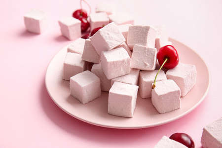 Plate with tasty sweet marshmallows and cherries on color background