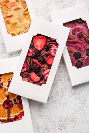 Handmade chocolate bars with fruits and berries on light background