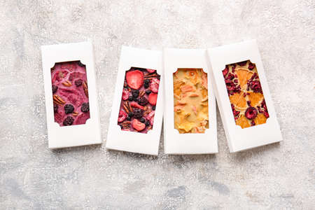 Handmade chocolate bars with fruits and berries on light background
