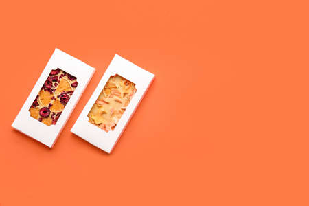 Handmade chocolate bars with fruits and berries on color background