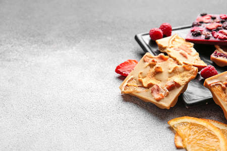 Handmade chocolate bars with fruits, berries and nuts on gray background