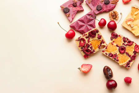 Handmade chocolate bars with fruits and berries on color background