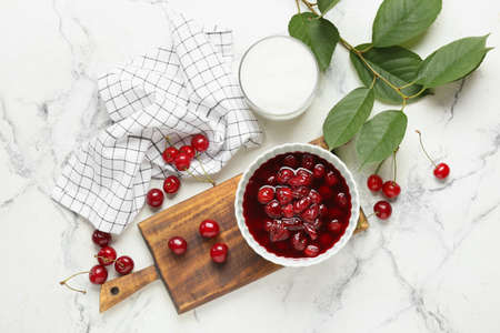 Bowl with tasty cherry jam and sugar on light backgroundの写真素材