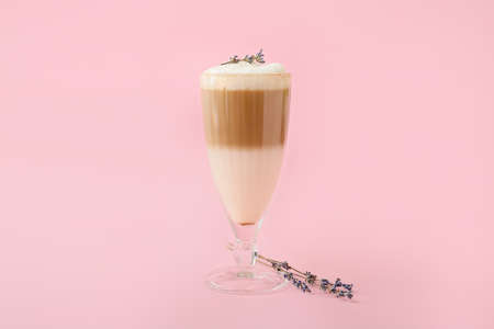 Glass of tasty lavender latte and flowers on color backgroundの写真素材