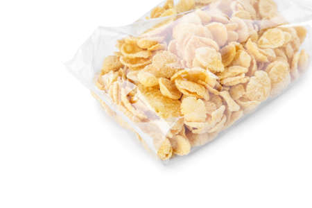 Bag with tasty corn flakes on white background, closeup