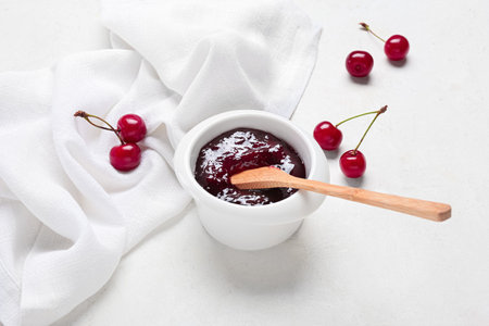 Bowl with tasty cherry jam on light backgroundの写真素材