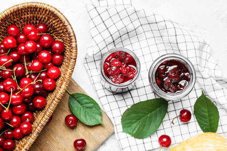 Ripe cherry and jam on light background, closeup