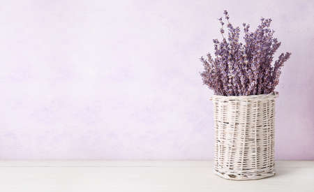 Wicker vase with beautiful lavender flowers on white backgroundの写真素材