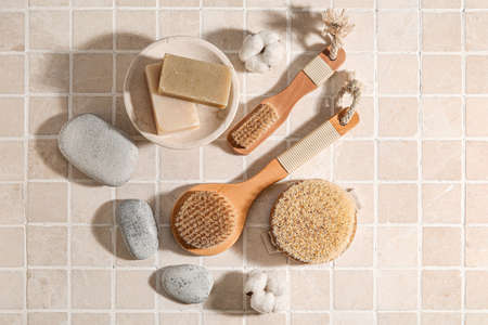 Different massage brushes and bath supplies on light tile backgroundの写真素材