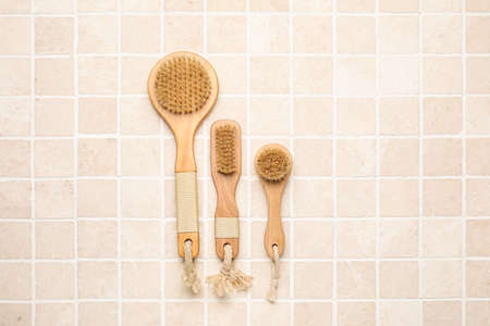 Different massage brushes on light tile background