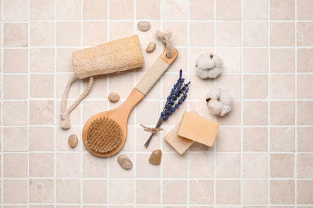 Composition with body brush and bath supplies on light tile background