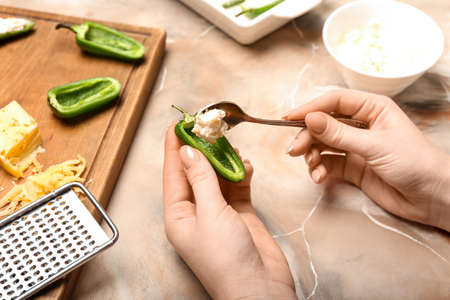 Woman cooking jalapeno poppers on color backgroundの写真素材