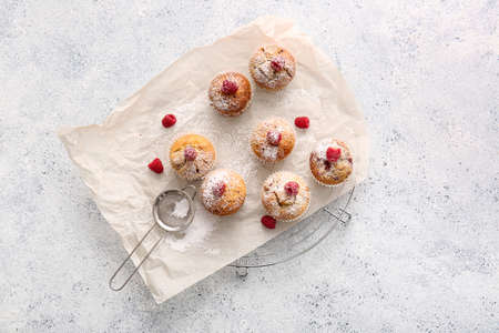 Grid with tasty raspberry muffins on light background