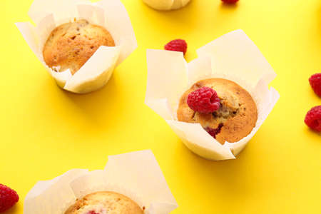 Tasty raspberry muffins on color background, closeup