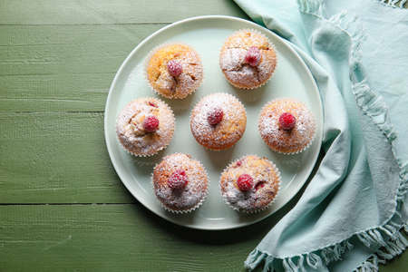 Tray with tasty raspberry muffins on wooden background