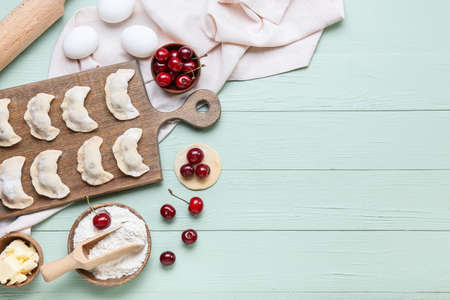 Composition with raw cherry dumplings on color wooden background