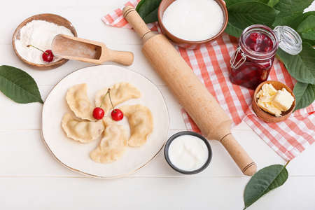 Composition with tasty cherry dumplings and sauce on light wooden backgroundの写真素材