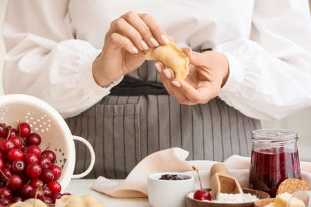 Woman preparing tasty cherry dumplings on table in kitchen, closeupの写真素材