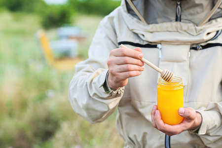Beekeeper with honey in jar at apiary