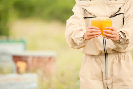 Female beekeeper with honey at apiaryの写真素材