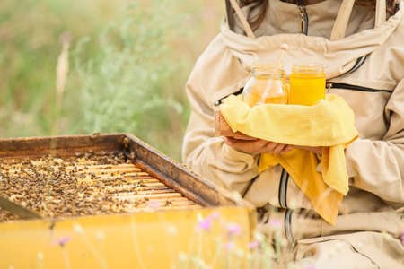 Female beekeeper with honey at apiaryの写真素材