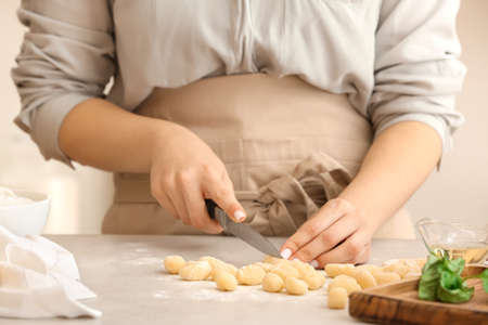 Woman preparing tasty gnocchi at table in kitchen, closeupの写真素材