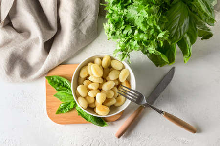 Bowl with tasty gnocchi on light background