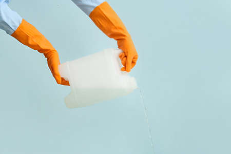 Man pouring out liquid from plastic canister on color backgroundの写真素材