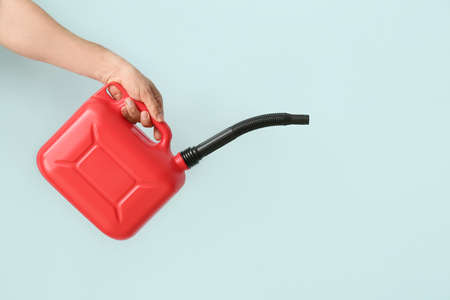 Male hand holding canister with rubber nozzle on color background