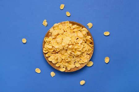 Plate with tasty cornflakes on color background
