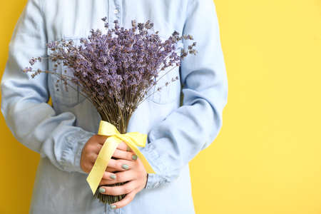 Woman with beautiful lavender flowers on color backgroundの写真素材