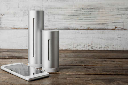 Digital weather station and mobile phone on wooden table