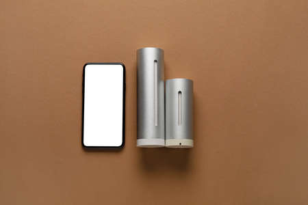 Digital weather station and mobile phone on brown background