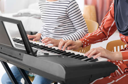 Private Muslim music teacher giving lesson to little girl at home