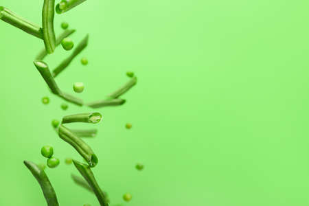 Flying green beans and peas on color background