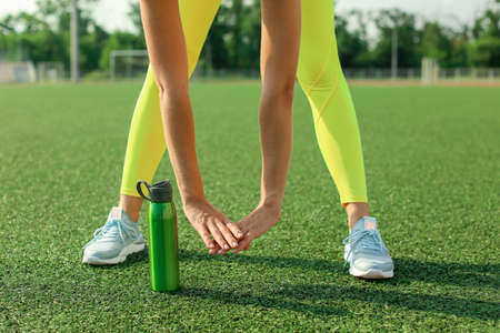 Young woman training on grass at sport stadium, closeup