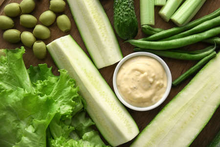Board with different green vegetables and bowl with sauce, closeupの写真素材