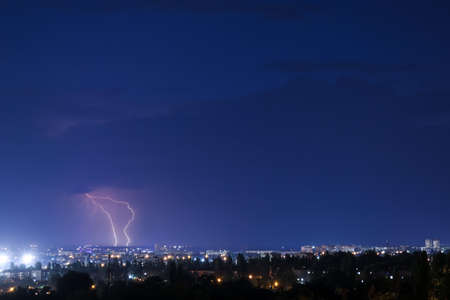 Dark sky with lightning over night city