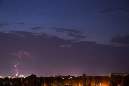 Dark sky with lightning over night city