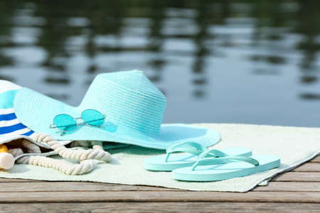 Stylish flip-flops and beach accessories on wooden pier