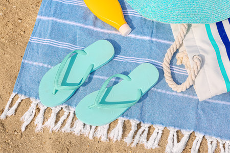 Stylish flip-flops and beach accessories on sand, closeup